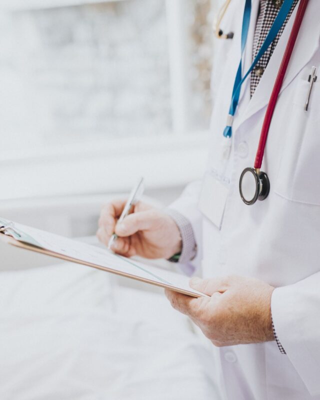 physician-noting-down-symptoms-patient-vertical